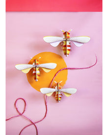  Three paper dragonflies on a pink background with a red border