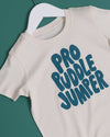 Beige t-shirt with 'Pro Puddle Jumper' text on a hanger against a green background