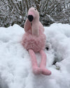 Knitted flamingo toy in the snow with a snowy background