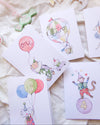 Set of birthday cards with cartoon monkey characters and balloons on a soft surface.
