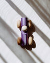 Wooden toy car with a purple body and brown wheels on a light background