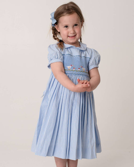 Young girl wearing a blue checkered dress with a white background