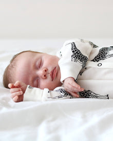  Newborn baby sleeping in a crib with a black and white patterned blanket