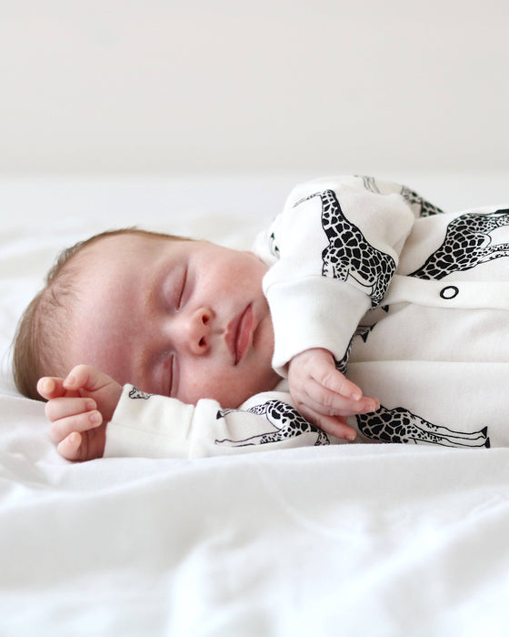 Newborn baby sleeping in a crib with a black and white patterned blanket
