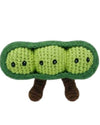 Crocheted green pea pod with small black eyes and brown legs on a white background