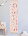 Children's growth chart with cartoon characters on a light blue wall.