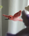 Pink felted bird toy against a blurred background