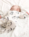 Baby wearing a onesie with penguin pattern lying on a white surface