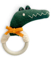 Knitted crocodile-shaped teething ring with a wooden ring on a white background
