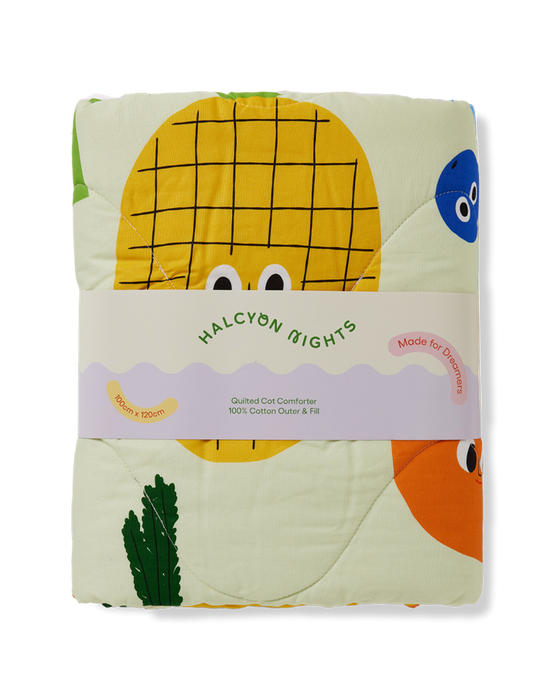 Folded quilt with cartoon pineapple design and 'Halcyon Nights' branding on a white background