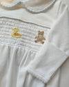 Close-up of a white garment with embroidered bear designs on a neutral background