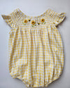 Yellow checkered baby bloomers with floral embellishments on a light gray background