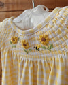 Yellow checkered dress with floral embroidery on a wooden surface