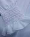 Close-up of white fabric with pink embroidery on a light blue background