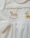 Close-up of a white garment with embroidered monkey and duck designs.