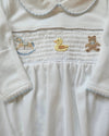 Close-up of a white garment with embroidered teddy bear designs on a light background