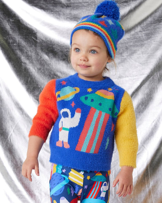 Child wearing a colorful sweater with space-themed design and a matching hat against a silver background