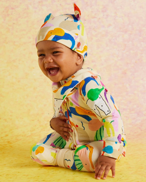 Baby wearing a colorful outfit with animal prints on a yellow background