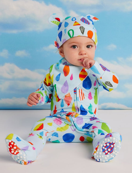 Baby in colorful outfit with cloud pattern against a blue sky background